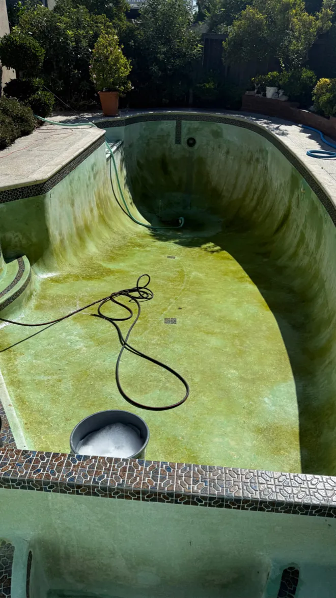 Drained pool with heavy green staining before acid wash treatment in Huntington Beach, CA