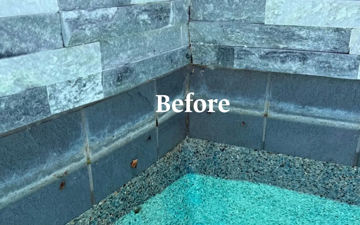 Textured spa tile and stonework with a white scale band before cleaning in Huntington Beach, CA