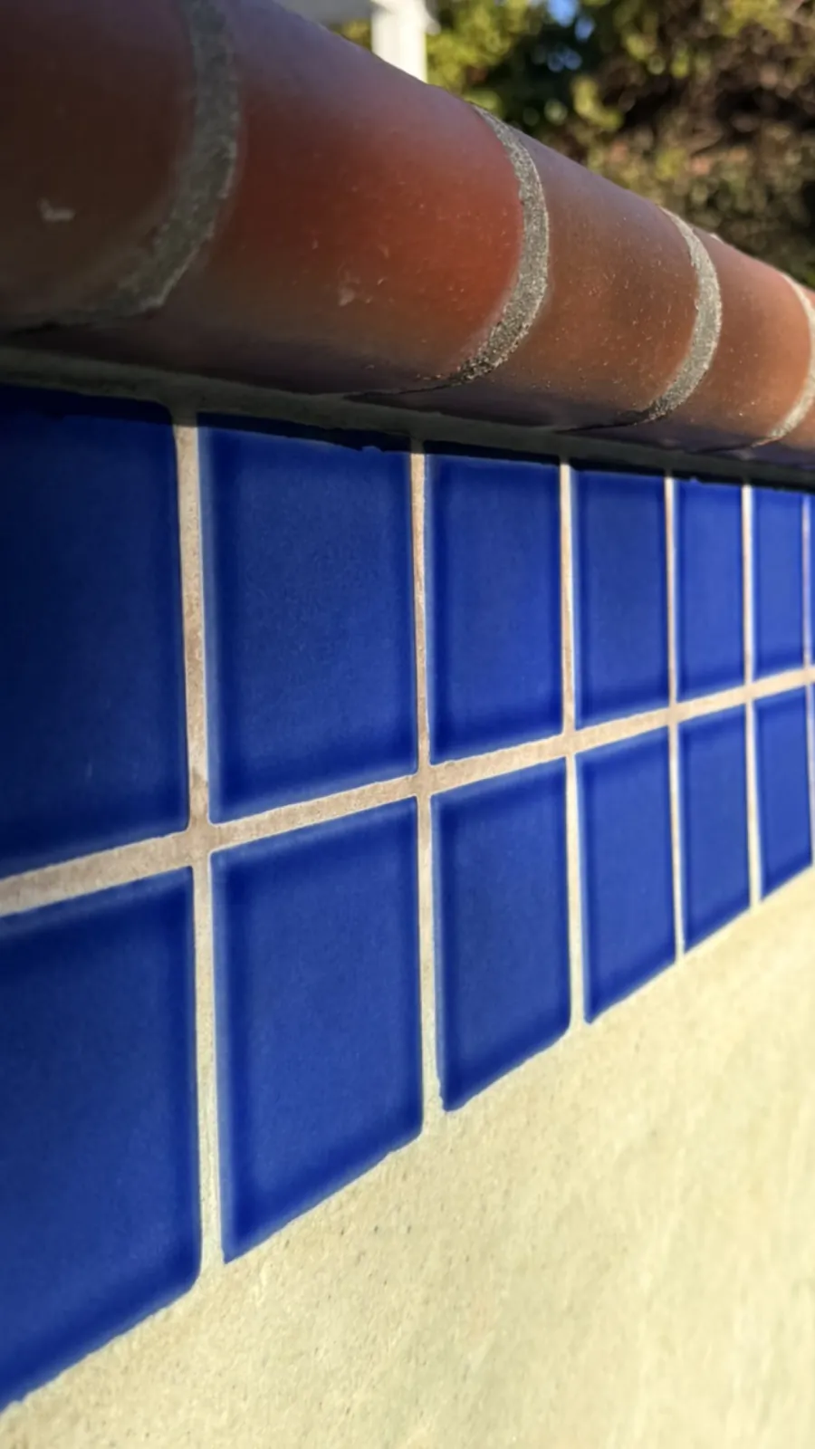 Blue pool wall tile with mineral deposits removed after professional cleaning in Huntington Beach, CA