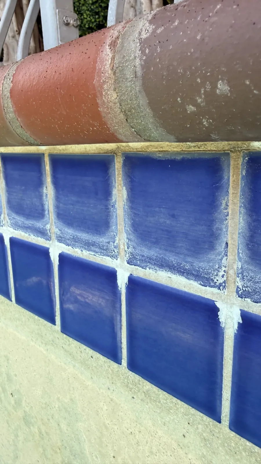 Blue pool wall tile streaked with white mineral deposits before cleaning in Huntington Beach, CA