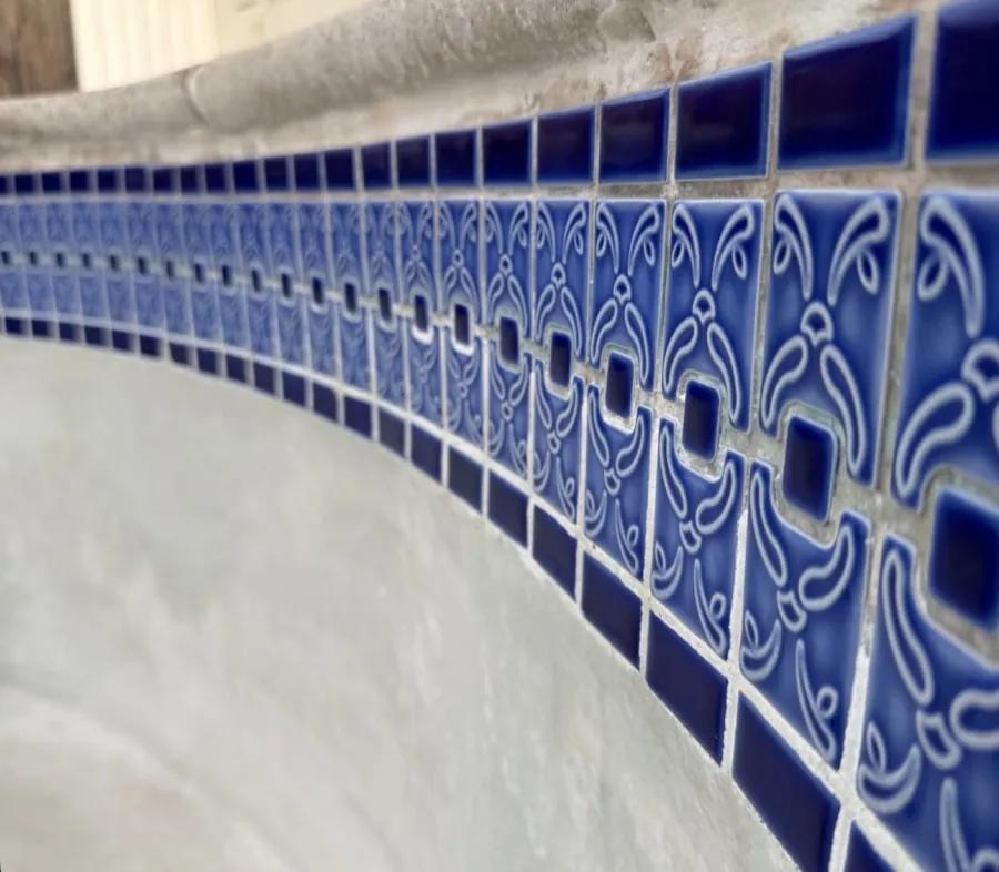 Decorative blue pool waterline tile restored after calcium removal in Huntington Beach, CA