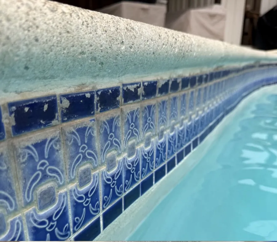 Decorative blue pool waterline tile covered in calcium scale before professional cleaning in Huntington Beach, CA
